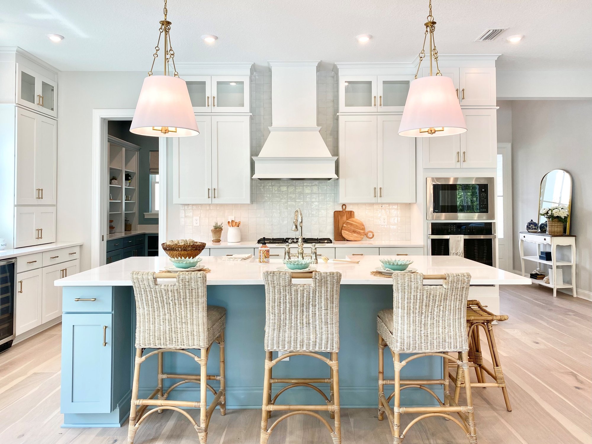 New construction kitchen with white cabinets, tile backsplash and blue eat in island.